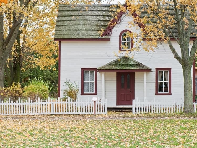 White house surrounded by picket fence on autumn day