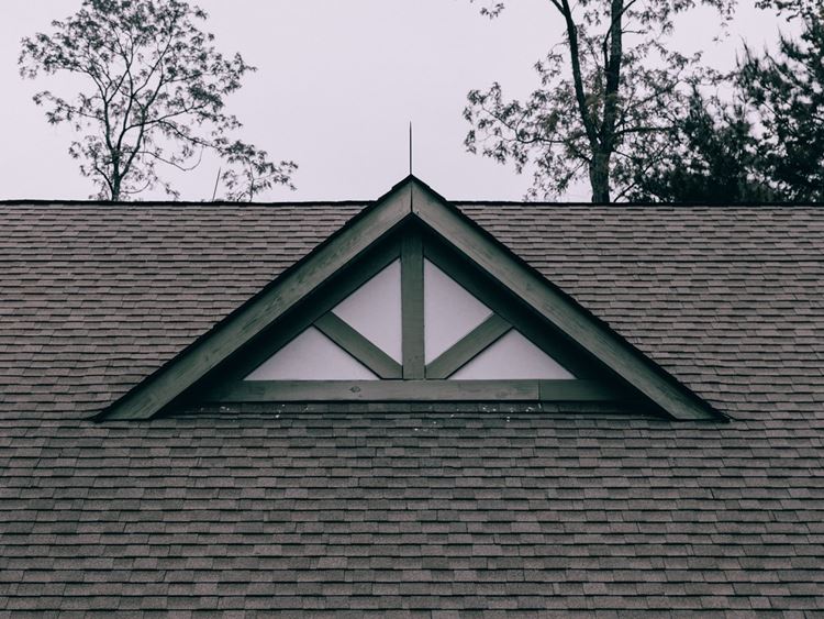Gray shingled roof with white and blue awning on residential home