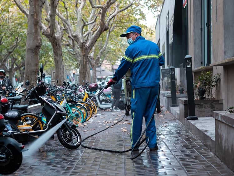 Professional power washer cleaning brick pavement outside of apartment complex