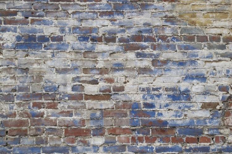 Red brick outdoor wall stained with blue and gray paint residue