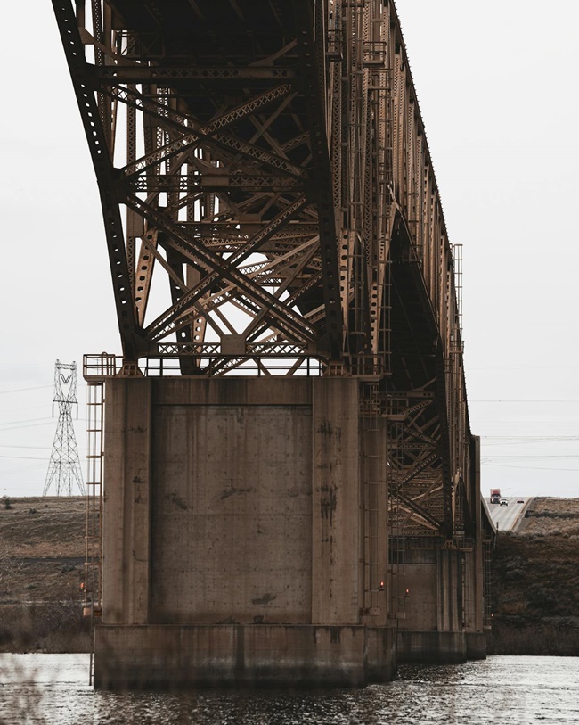 Large steel bridge with rusted concrete base above water