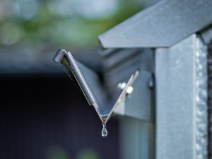 Water dripping from edge of stainless steel rain gutter